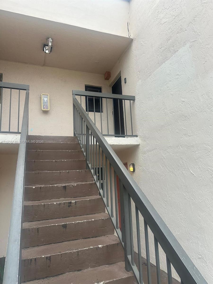 An exterior view shows a concrete staircase leading to an upper-level landing with metal railings — 855 NE 209th St # 34, Miami FL 33179, MIAMI, FL