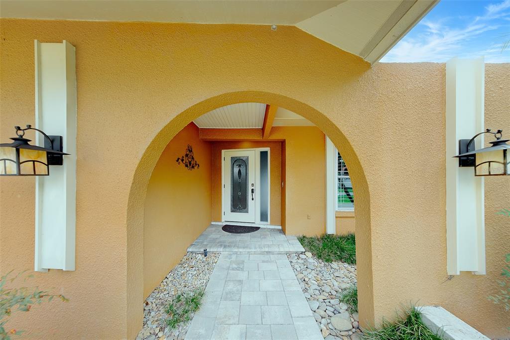 A paved walkway leads through an arched entryway to a white front door — 4119 CROSSWATER DRIVE, TAMPA, FL