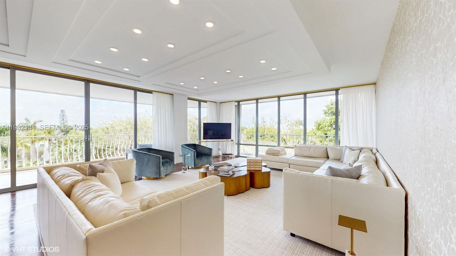 A bright living room features white sofas, gold coffee tables, and floor-to-ceiling windows — 10155 Collins Ave # 410, Bal Harbour FL 33154, BAL HARBOUR, FL