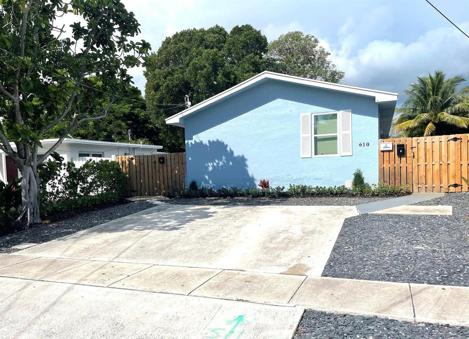 A light blue house with a concrete driveway and a wooden fence in the front yard — 610 SE 2nd Avenue, Delray Beach FL 33483, DELRAY BEACH, FL