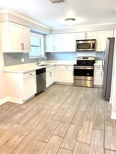 A kitchen with white cabinets, stainless steel appliances, gray subway tile backsplash, and wood-look flooring — 610 SE 2nd Avenue, Delray Beach FL 33483, DELRAY BEACH, FL
