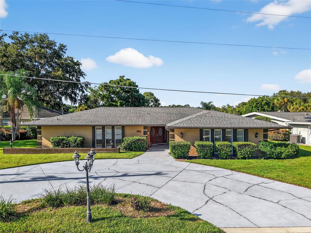 A single-story house with a tan exterior, a gray roof, and a cracked concrete driveway — 2514 TUSCARORA TRAIL, MAITLAND, FL