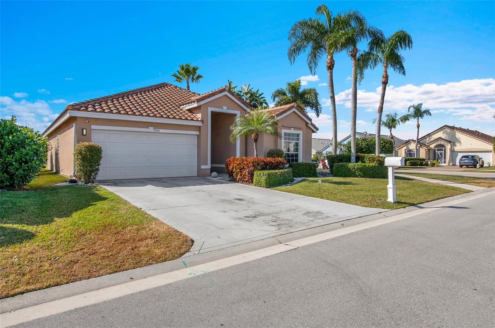 A single-story tan house with a tile roof and a concrete driveway under blue skies — 7491 Stirling Bridge Boulevard, Delray Beach FL 33446, DELRAY BEACH, FL