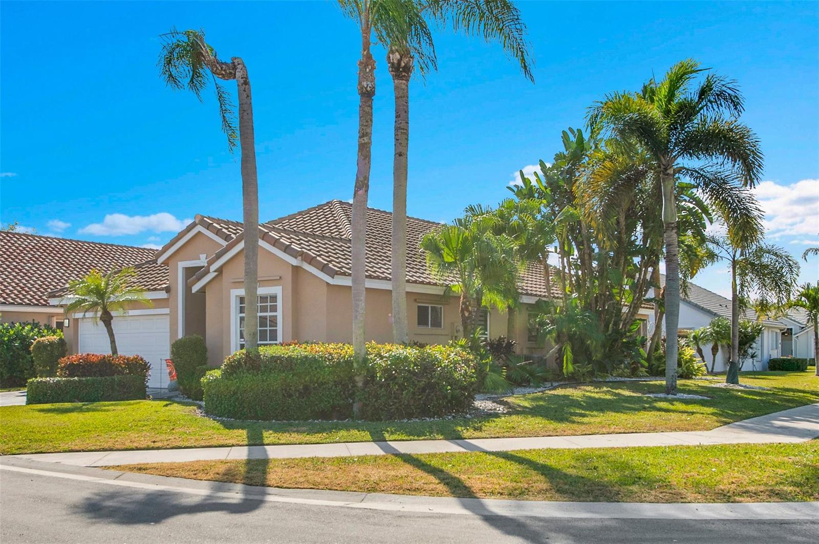 A tan, single-story house with a tile roof and palm trees sits on a corner lot — 7491 Stirling Bridge Boulevard, Delray Beach FL 33446, DELRAY BEACH, FL