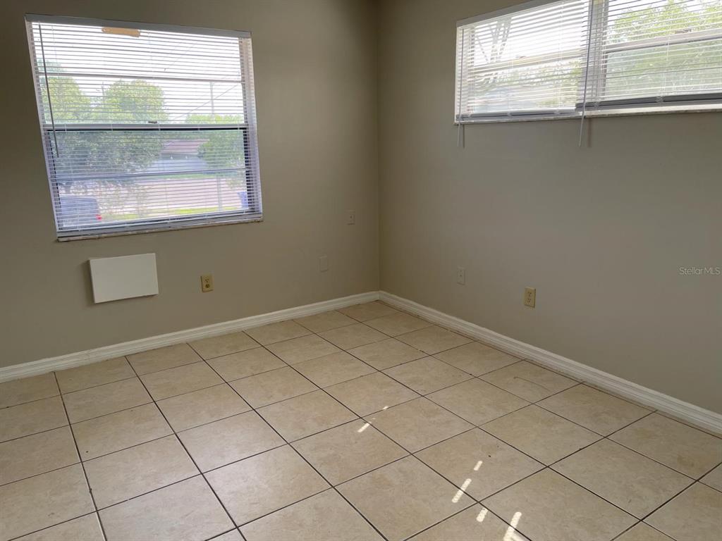 An empty room with beige tile flooring, two windows with blinds, and light-colored walls — 722 W COLUMBIA AVENUE UNIT 722, KISSIMMEE, FL