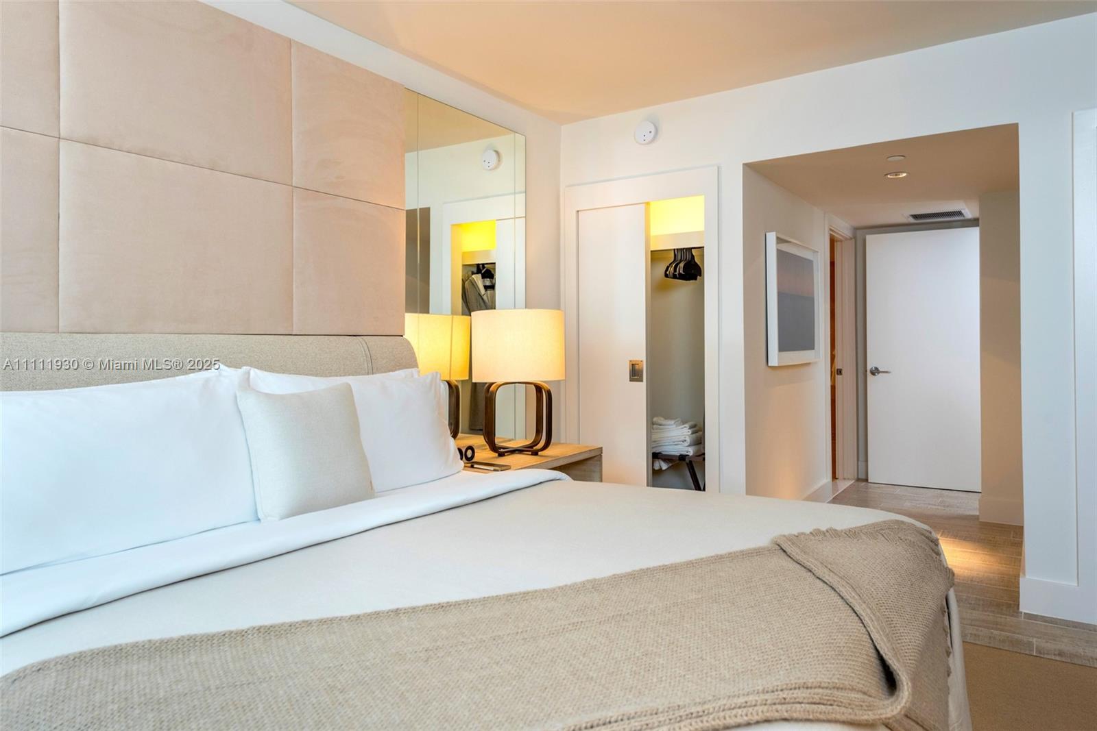 A bedroom features a bed with a beige headboard, a bedside lamp, and a closet — 102 24th St # 1106, Miami Beach FL 33139, MIAMI BEACH, FL