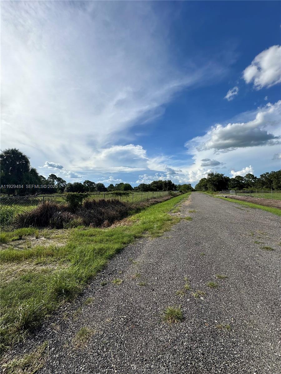 A gravel road runs alongside a fenced field under a cloudy blue sky — 420 S. CORAL ST., Clewiston FL 33440, CLEWISTON, FL