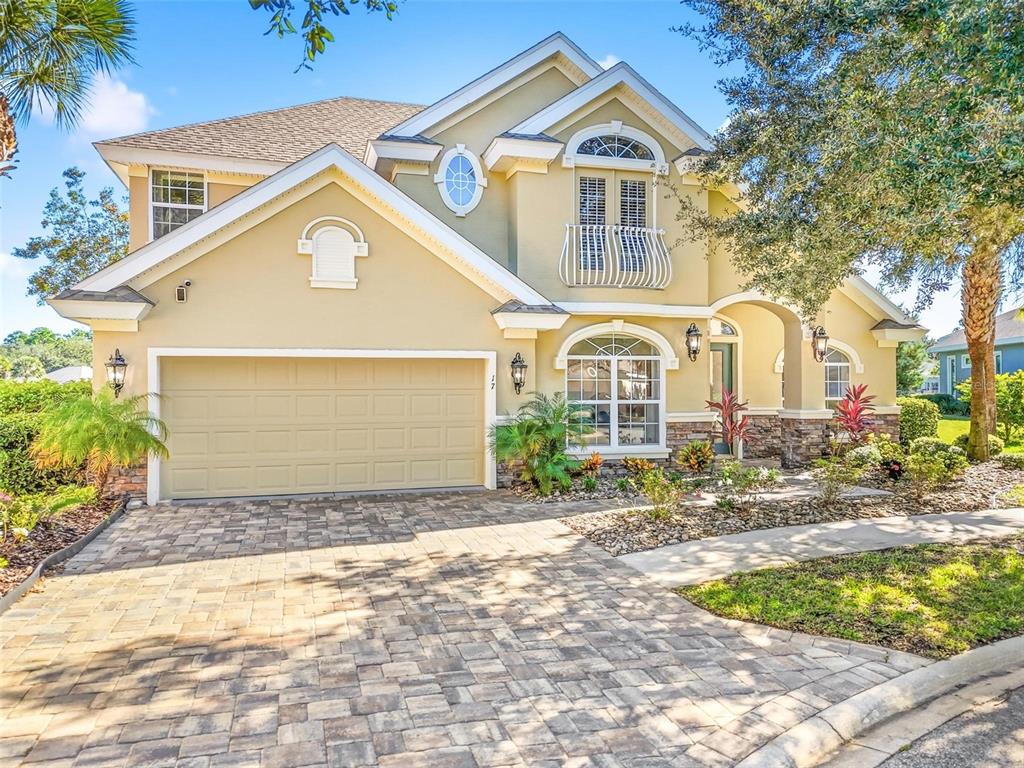 A two-story house with a beige stucco exterior, a paved driveway, and a front balcony — 17 SANDPIPER COURT, PALM COAST, FL