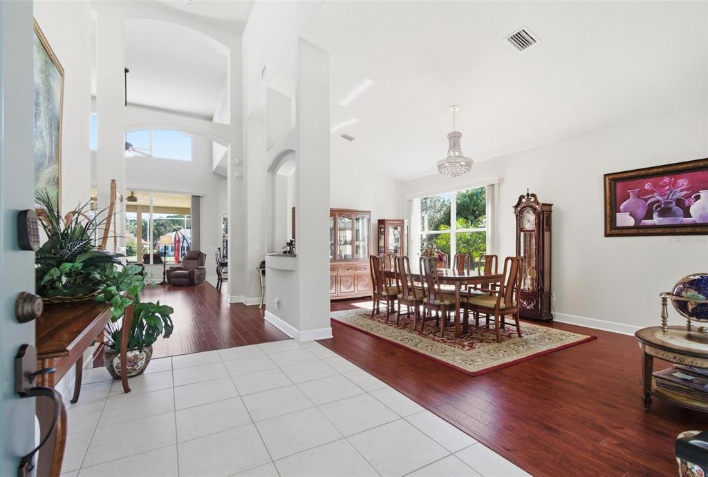 A bright dining room with hardwood floors, a chandelier, and a view into the living area — 17 SANDPIPER COURT, PALM COAST, FL