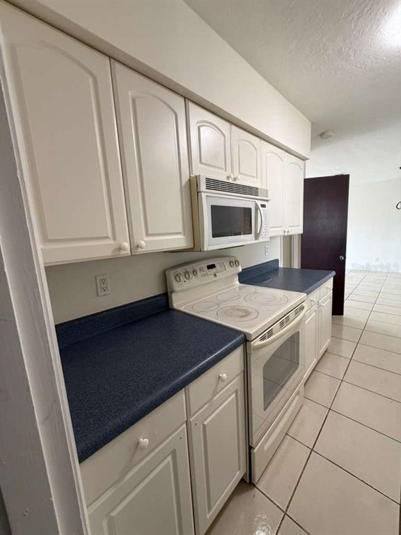 A kitchen features white cabinets, a blue countertop, a white stove, and a built-in microwave — 345 S VENICE BOULEVARD, VENICE, FL