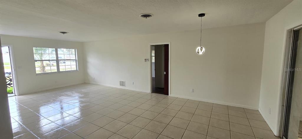 An open living area features light-colored tile flooring, white walls, and a modern pendant light — 345 S VENICE BOULEVARD, VENICE, FL