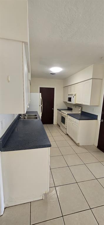 A kitchen features white cabinets, blue countertops, tile flooring, and a white refrigerator — 345 S VENICE BOULEVARD, VENICE, FL