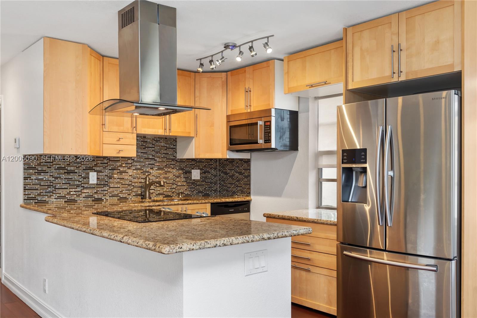 A kitchen features light wood cabinets, granite countertops, stainless steel appliances, and a mosaic backsplash — 854 Normandy R # 854, Delray Beach FL 33484, DELRAY BEACH, FL