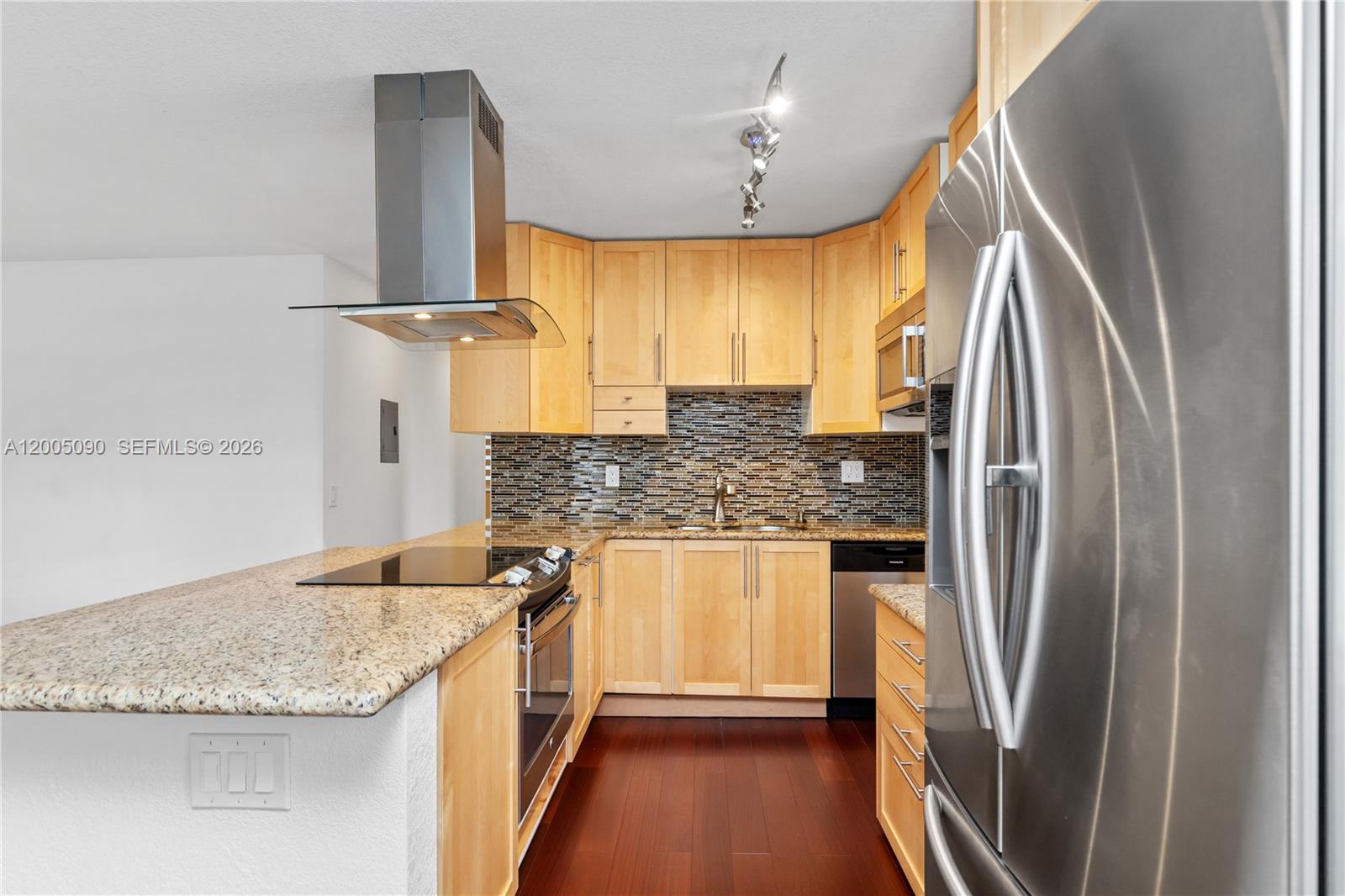 A kitchen features light wood cabinets, granite countertops, stainless steel appliances, and dark wood flooring — 854 Normandy R # 854, Delray Beach FL 33484, DELRAY BEACH, FL