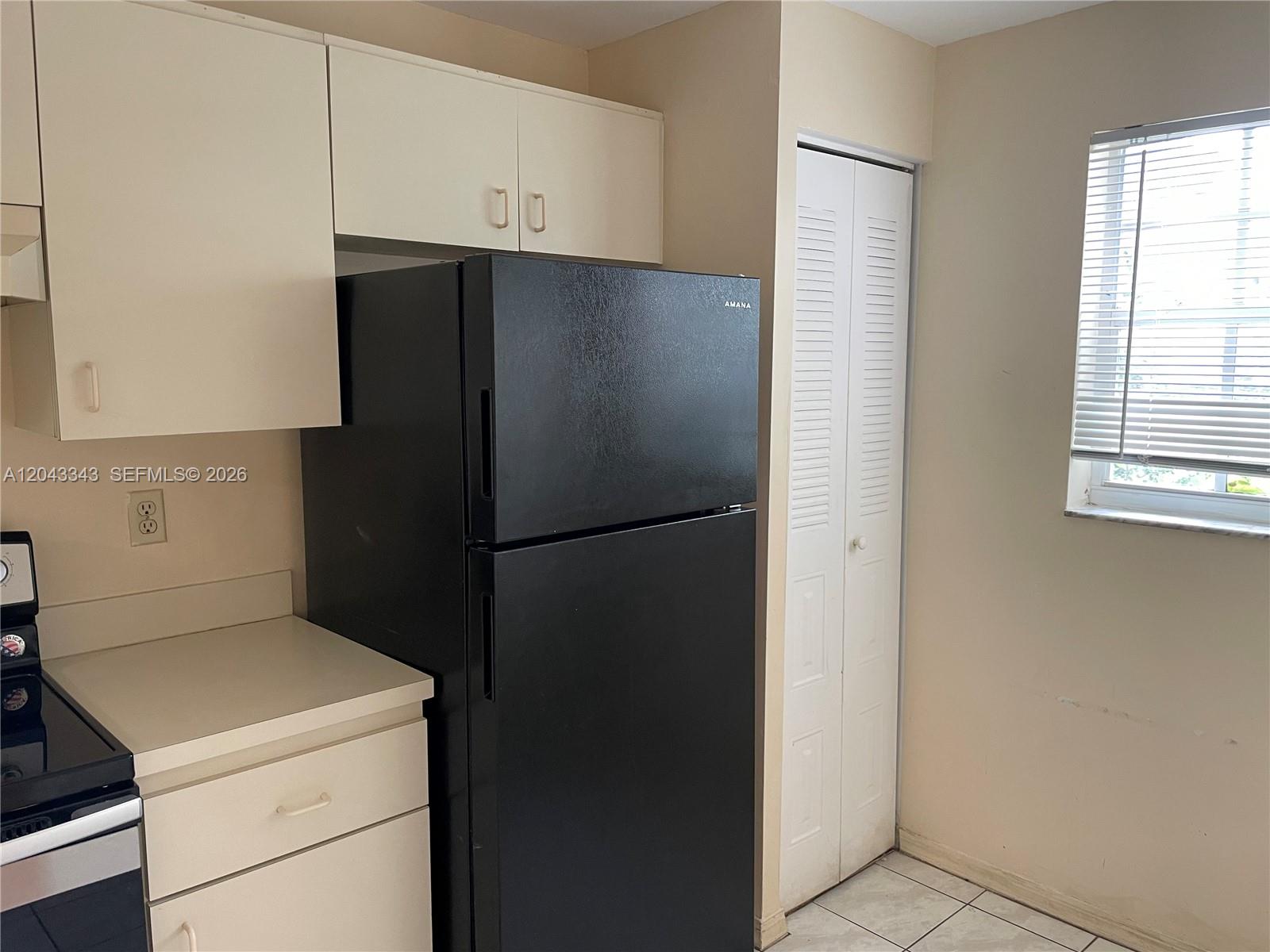 A kitchen features white cabinets, a black refrigerator, a stove, and a window with blinds — 426 NE 210th Cir Ter # 2, Miami FL 33179, MIAMI, FL