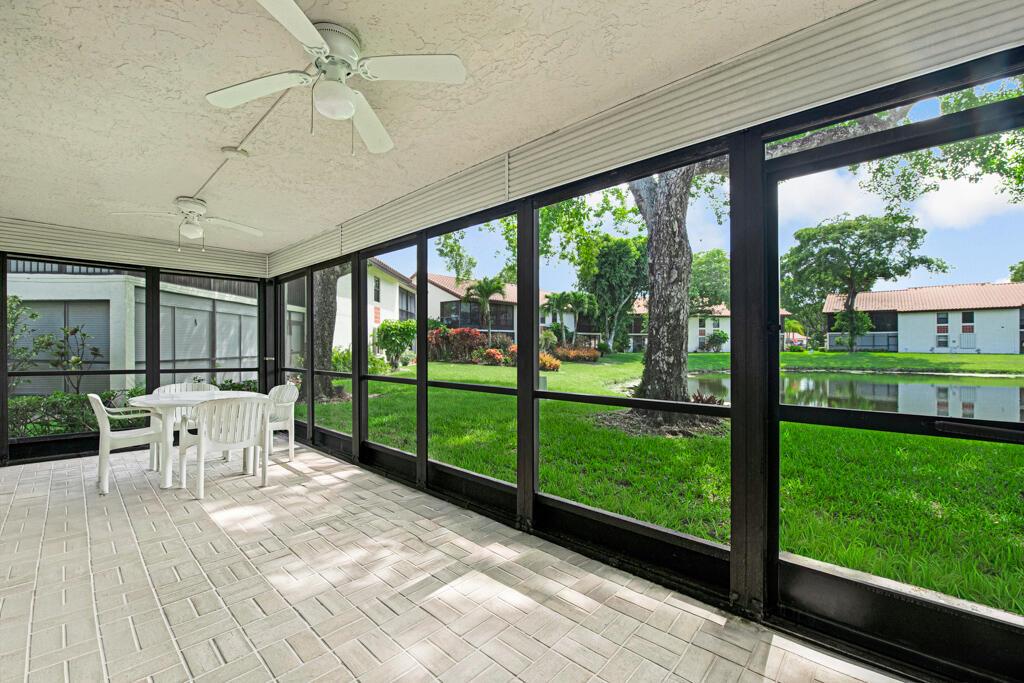 A screened-in patio with tile flooring, white furniture, and a view of a grassy pond — 10851 Palm Lake Avenue # 101, Boynton Beach FL 33437, BOYNTON BEACH, FL