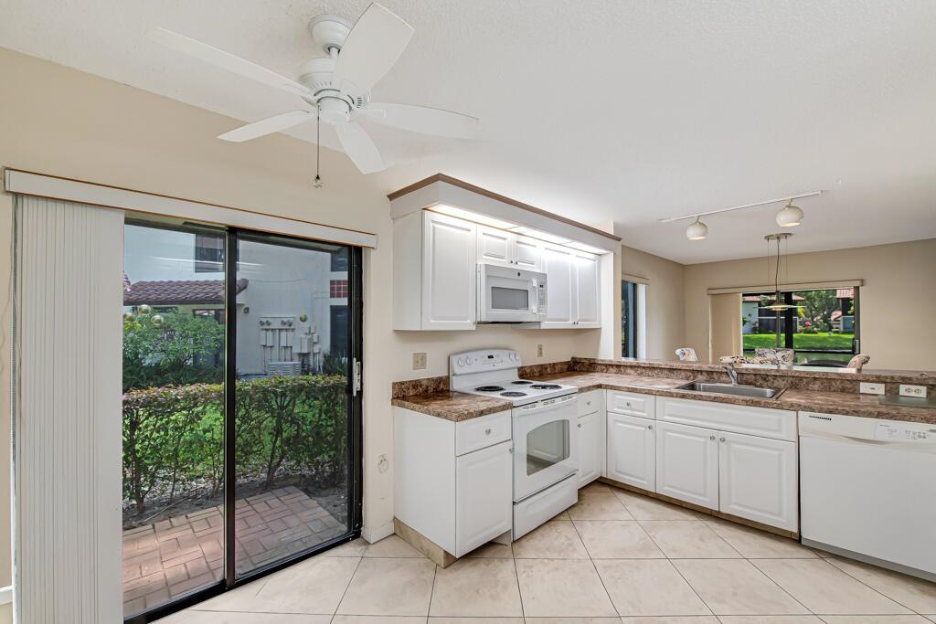 A kitchen with white cabinets, laminate countertops, and a sliding glass door to a patio — 10851 Palm Lake Avenue # 101, Boynton Beach FL 33437, BOYNTON BEACH, FL