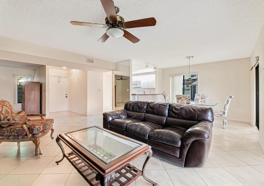 A living room with tile floors, a brown leather sofa, and a glass coffee table — 10851 Palm Lake Avenue # 101, Boynton Beach FL 33437, BOYNTON BEACH, FL