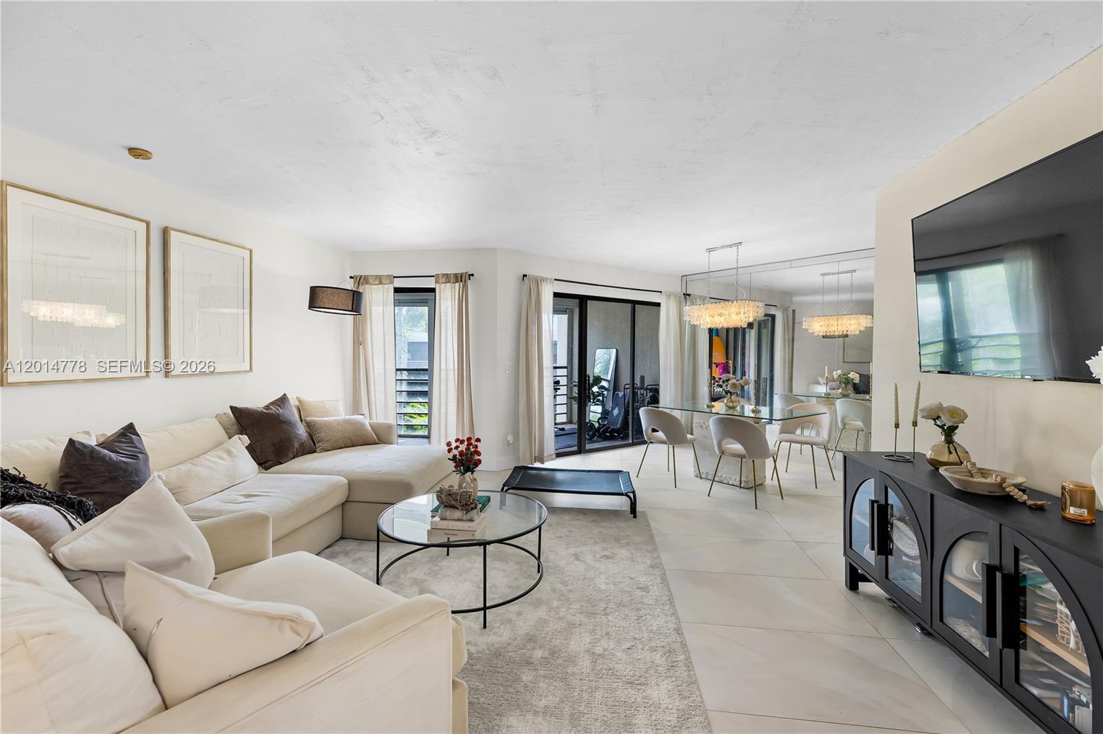 A bright living and dining area features a large sectional sofa, glass tables, and tile flooring — 5850 Camino Del Sol # 404, Boca Raton FL 33433, BOCA RATON, FL