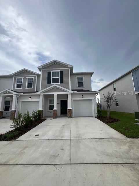 A two-story townhouse exterior features a concrete driveway, two garage doors, and gray siding — 2691 SKYLINE LOOP, KISSIMMEE, FL