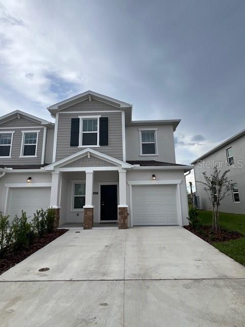A two-story townhouse exterior features gray siding, a white garage door, and a concrete driveway — 2691 SKYLINE LOOP, KISSIMMEE, FL