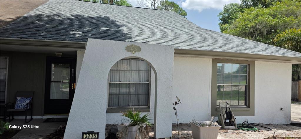 The exterior of a single-story house features a white stucco facade, an arched entryway, and a shingled roof — 3205 LAUREL DALE DRIVE, TAMPA, FL