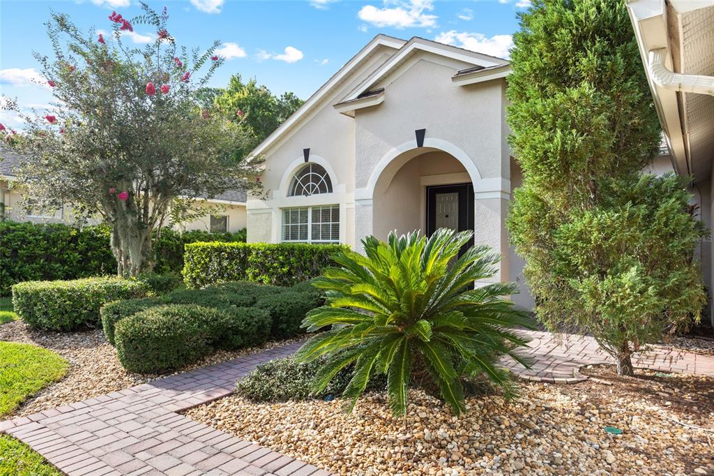 A paved walkway leads to the front entrance of a house with a landscaped yard — 16132 IVY LAKE DRIVE, ODESSA, FL