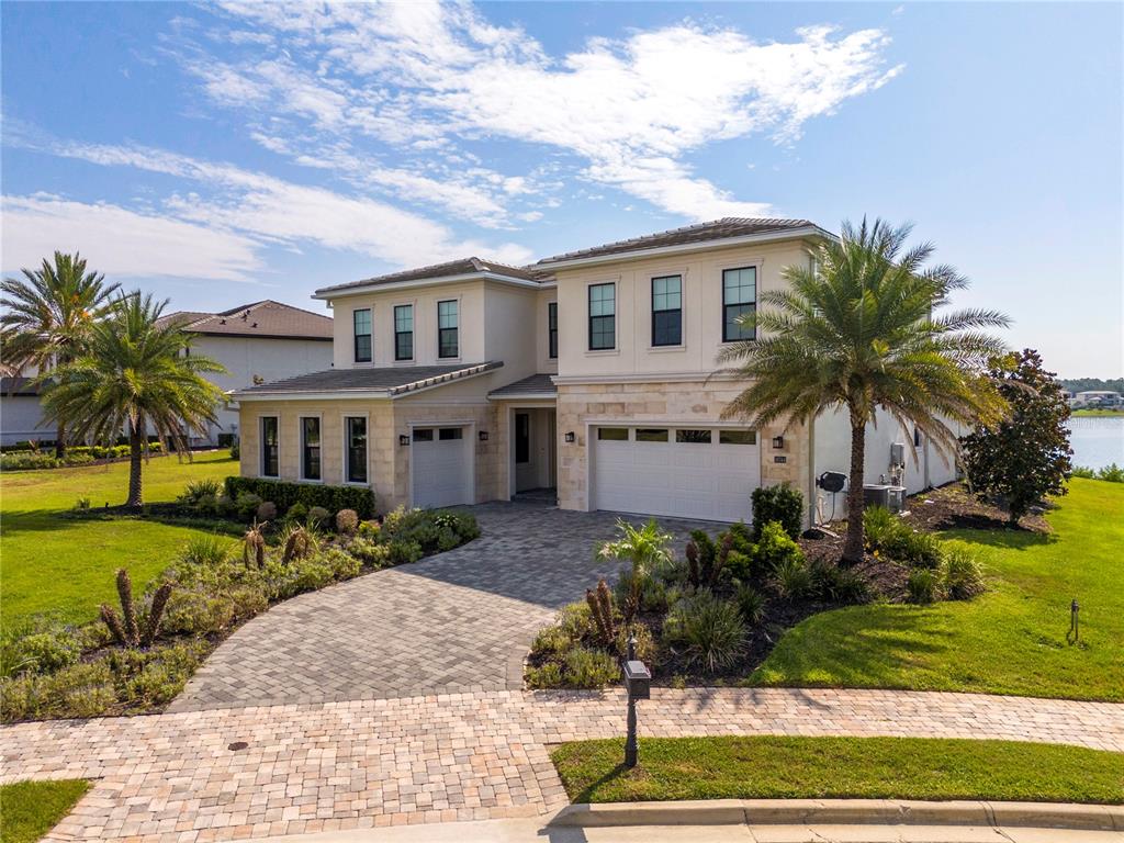 A two-story house with a stone facade, a paved driveway, and palm trees in the yard — 16744 BOLSENA DRIVE, BELLA COLLINA, FL