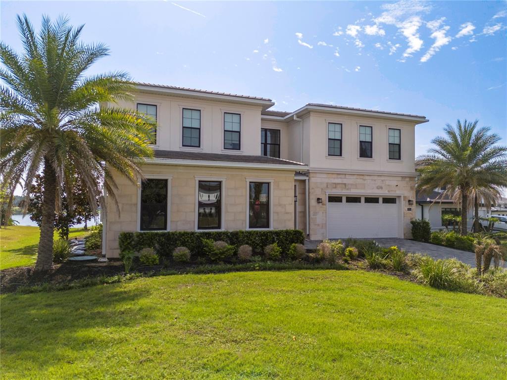 A two-story house with a stone facade, a two-car garage, and palm trees — 16744 BOLSENA DRIVE, BELLA COLLINA, FL