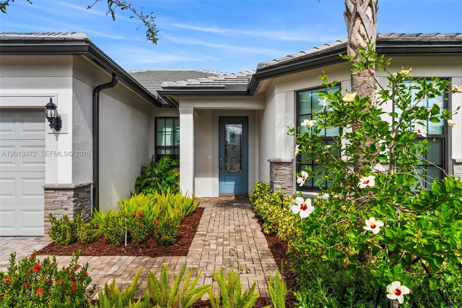 The exterior of a modern house features a blue front door and a brick walkway — 2715 Primrose Pl, Oakland Park FL 33309, OAKLAND PARK, FL