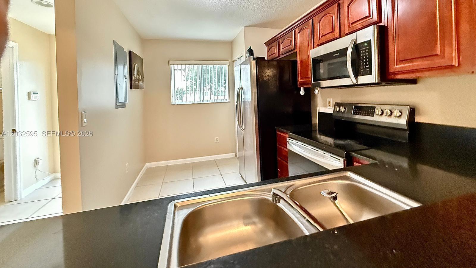 A kitchen features dark countertops, stainless steel appliances, and wood cabinetry — 6631 Winfield Blvd # 6, Margate FL 33063, MARGATE, FL
