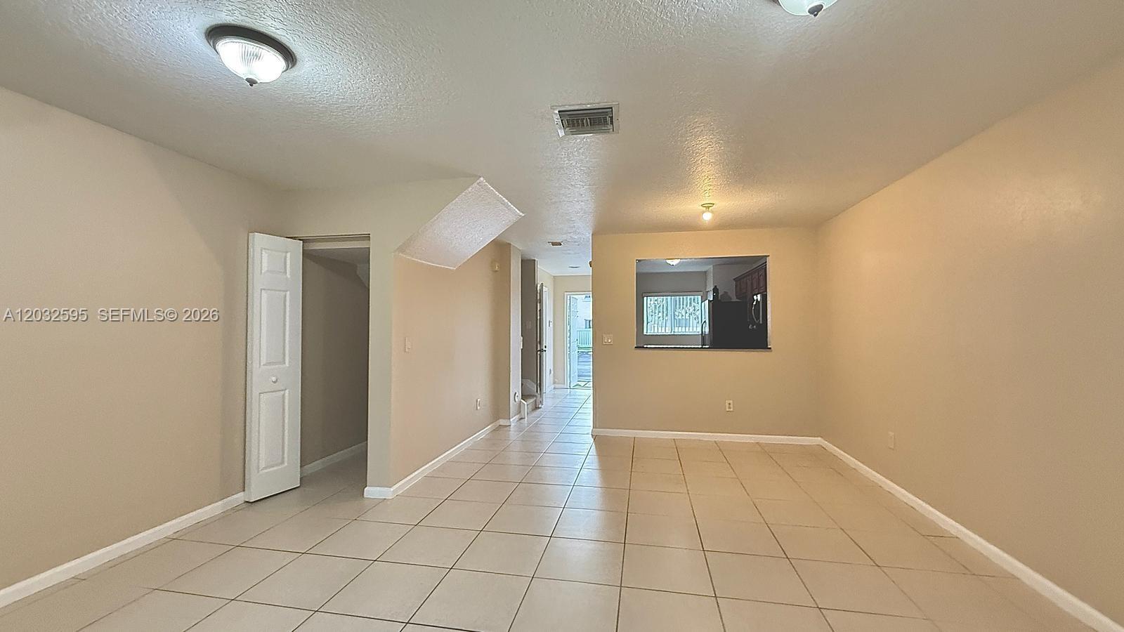 An interior view shows a tiled living area with a pass-through window to the kitchen — 6631 Winfield Blvd # 6, Margate FL 33063, MARGATE, FL
