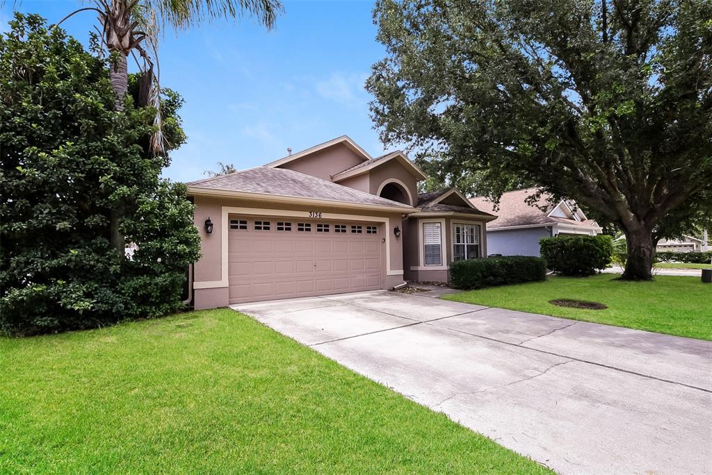 A tan single-story house with a two-car garage and a concrete driveway — 3136 LINDERA DRIVE, DELTONA, FL