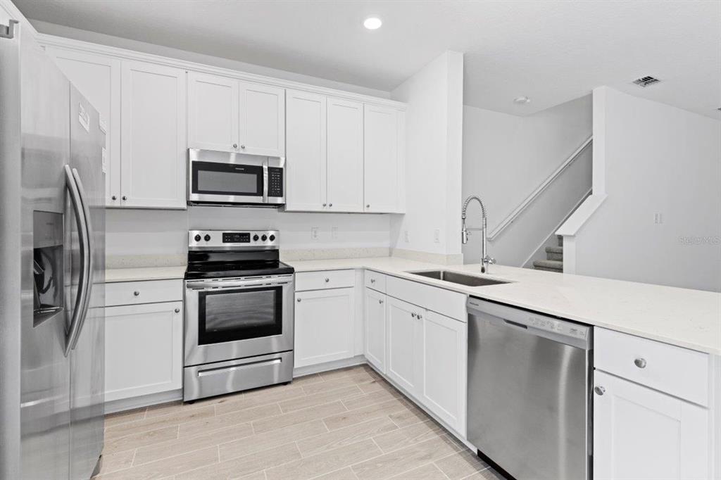 A kitchen with white cabinets, stainless steel appliances, and light-colored countertops — 698 NW 126TH TERRACE, NEWBERRY, FL