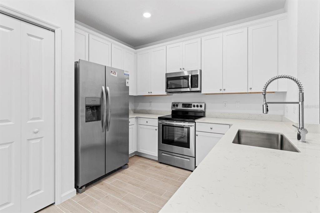 A modern kitchen features white cabinets, stainless steel appliances, and light-colored countertops — 698 NW 126TH TERRACE, NEWBERRY, FL