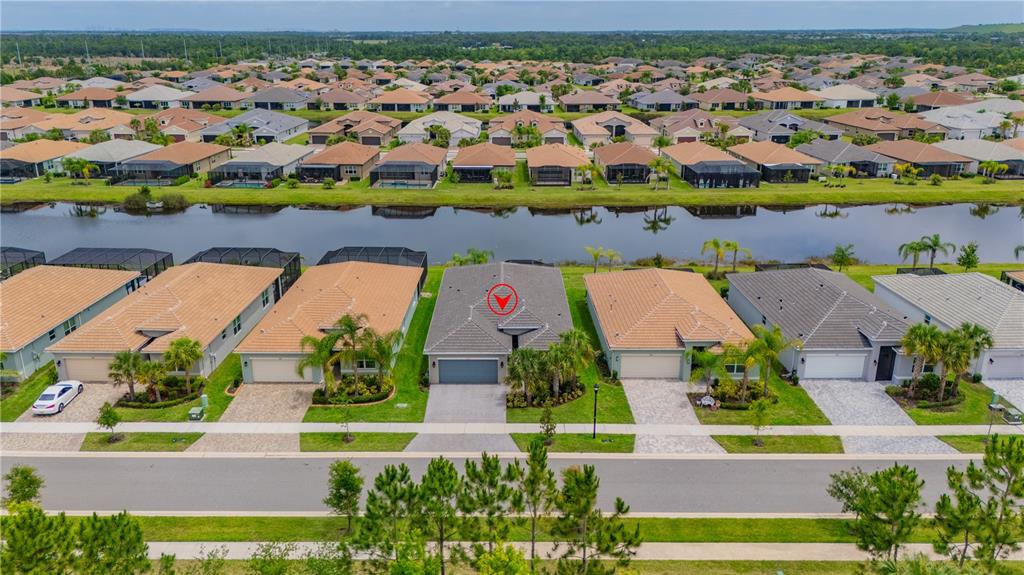 An aerial view shows a suburban neighborhood with houses, a canal, and a red marker — 4844 AVILA LAKES DRIVE, WIMAUMA, FL