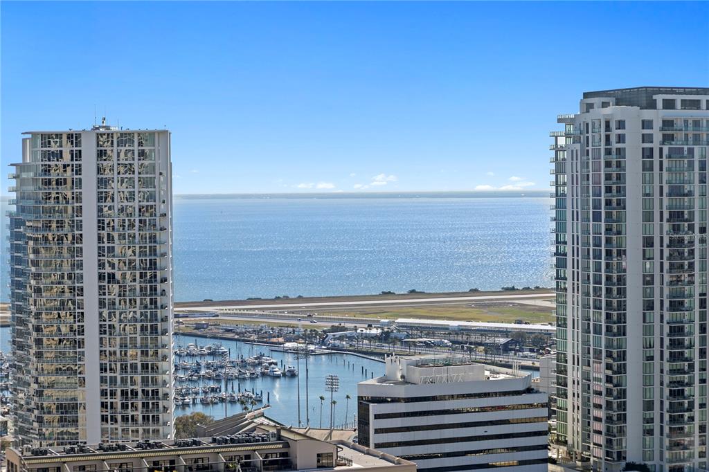 An elevated view shows two high-rise buildings framing a marina, an airport runway, and water — 400 CENTRAL AVENUE UNIT 2806, ST PETERSBURG, FL