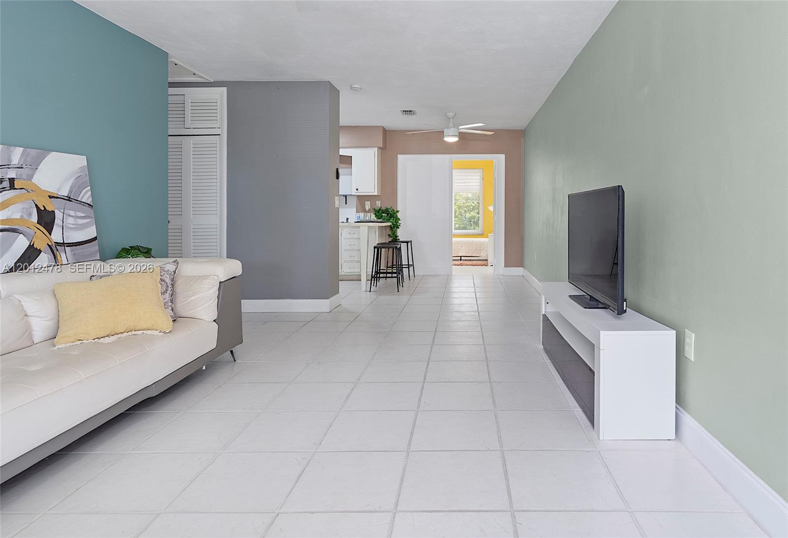 A living room with tile floors, a white sofa, and a television on a stand — 1817 NW 60th Ave # G, Sunrise FL 33313, SUNRISE, FL