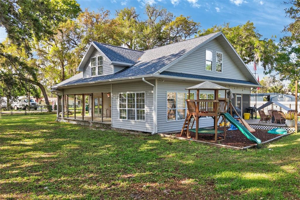 A gray-sided house with a wrap-around porch and a wooden playset in the backyard — 5572 S MARLIN POINT, FLORAL CITY, FL