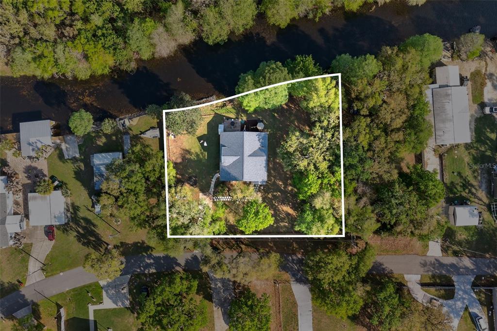 An aerial view shows a house situated on a wooded lot bordering a river — 5572 S MARLIN POINT, FLORAL CITY, FL