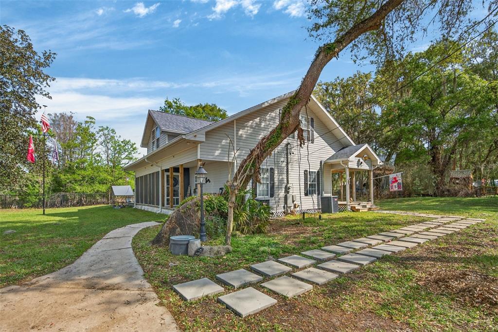 A two-story house with light siding, a screened porch, and a stone walkway in front — 5572 S MARLIN POINT, FLORAL CITY, FL