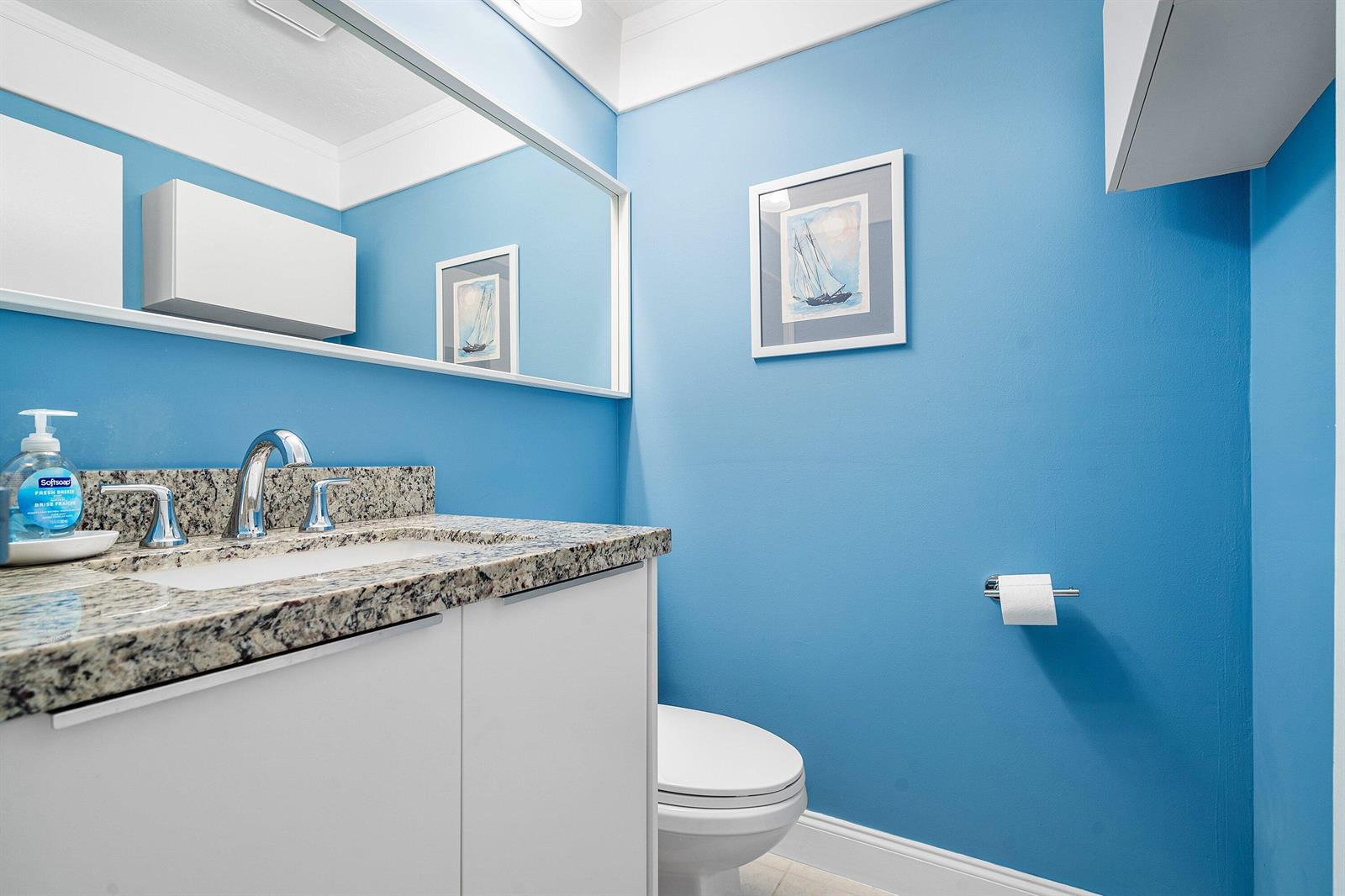 A bathroom features blue walls, a granite countertop, a white vanity, and a framed print — 142 Brittany Terrace, Delray Beach FL 33446, DELRAY BEACH, FL