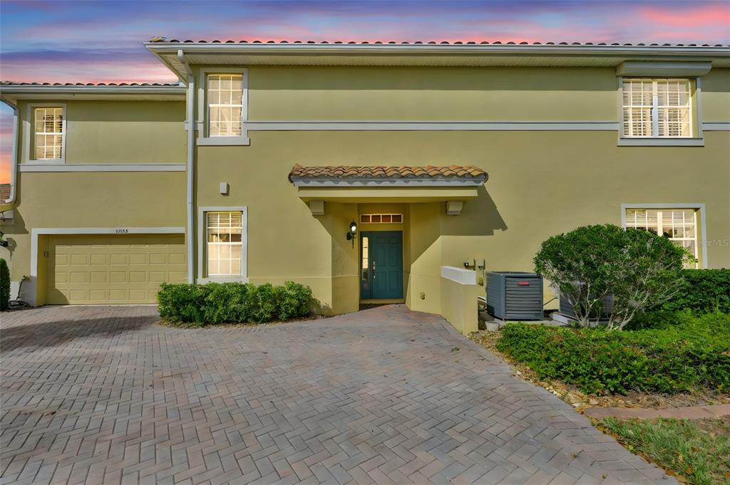 A two-story yellow stucco house features a paved driveway, a garage, and a front entrance — 1324 EMERALD DUNES DRIVE, SUN CITY CENTER, FL