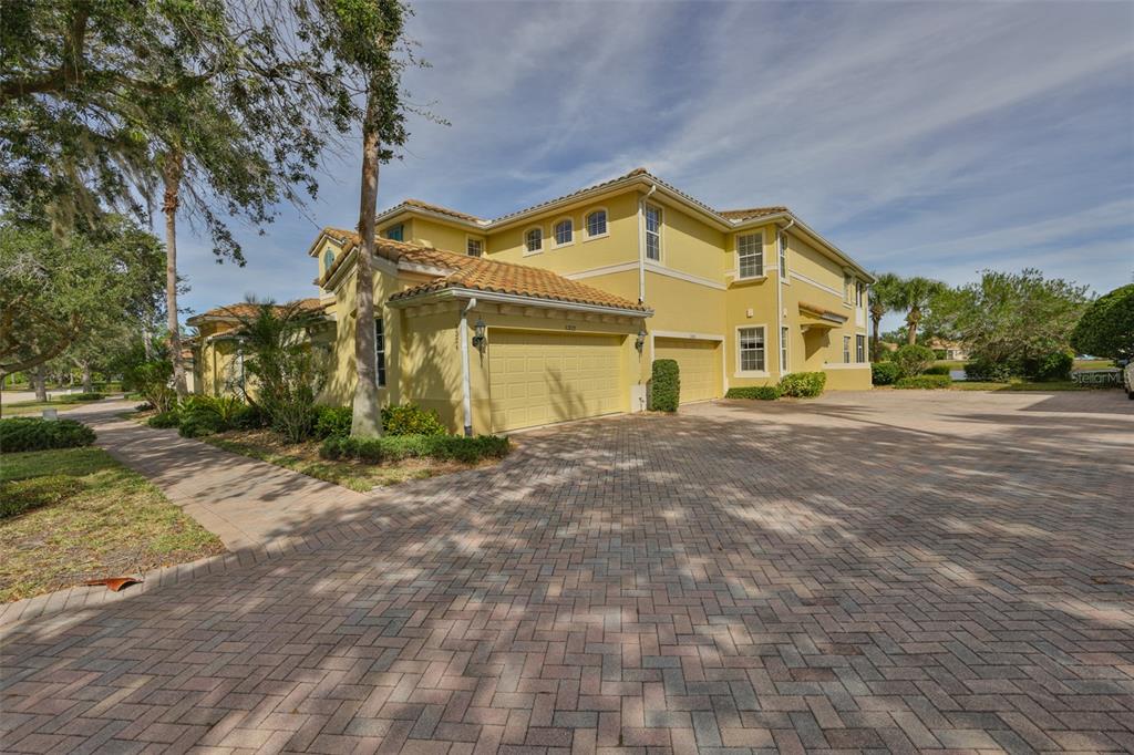 A yellow two-story house with a tiled roof and a paved driveway — 1324 EMERALD DUNES DRIVE, SUN CITY CENTER, FL