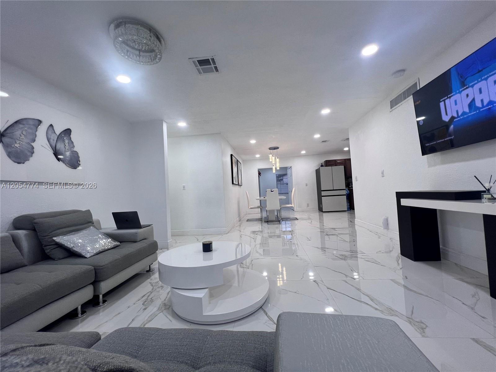 A living room features white marble floors, a grey sectional sofa, and a wall-mounted television — 2001 SW 85th Ave, North Lauderdale FL 33068, NORTH LAUDERDALE, FL