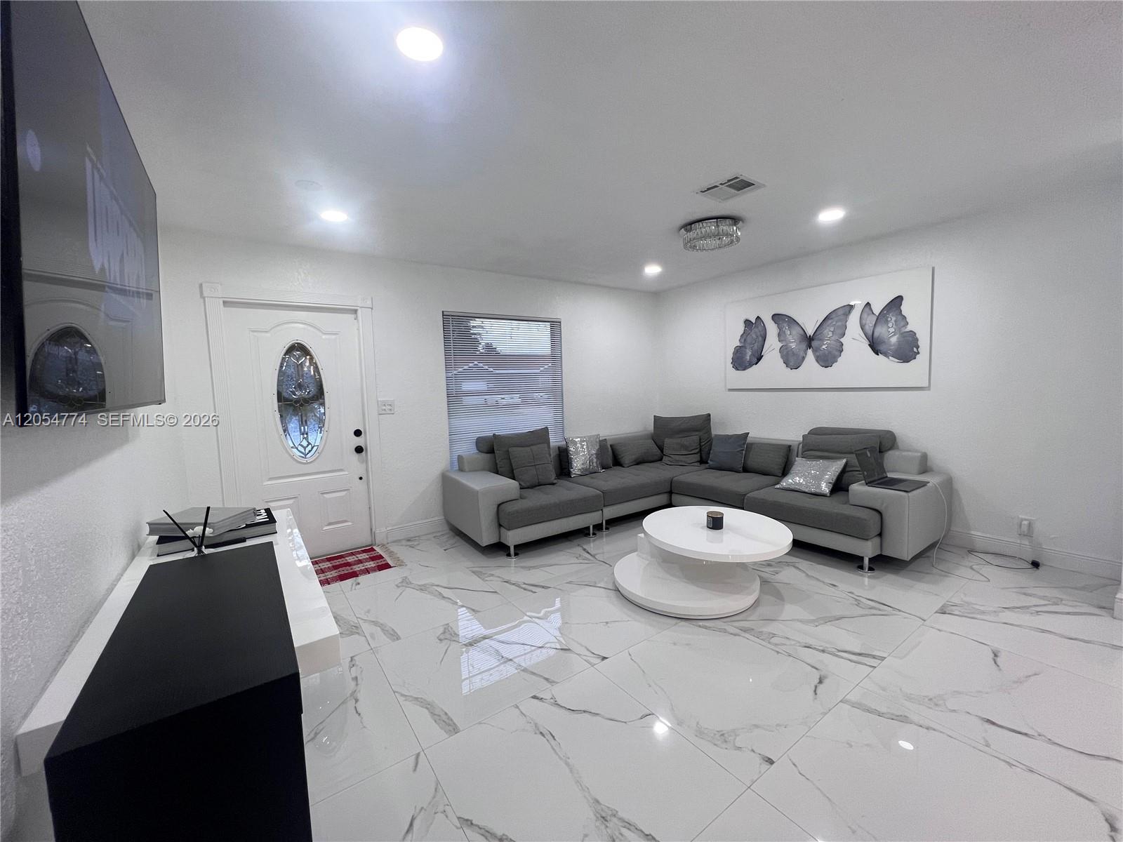 A living room features white marble floors, a gray sectional sofa, and butterfly wall art — 2001 SW 85th Ave, North Lauderdale FL 33068, NORTH LAUDERDALE, FL