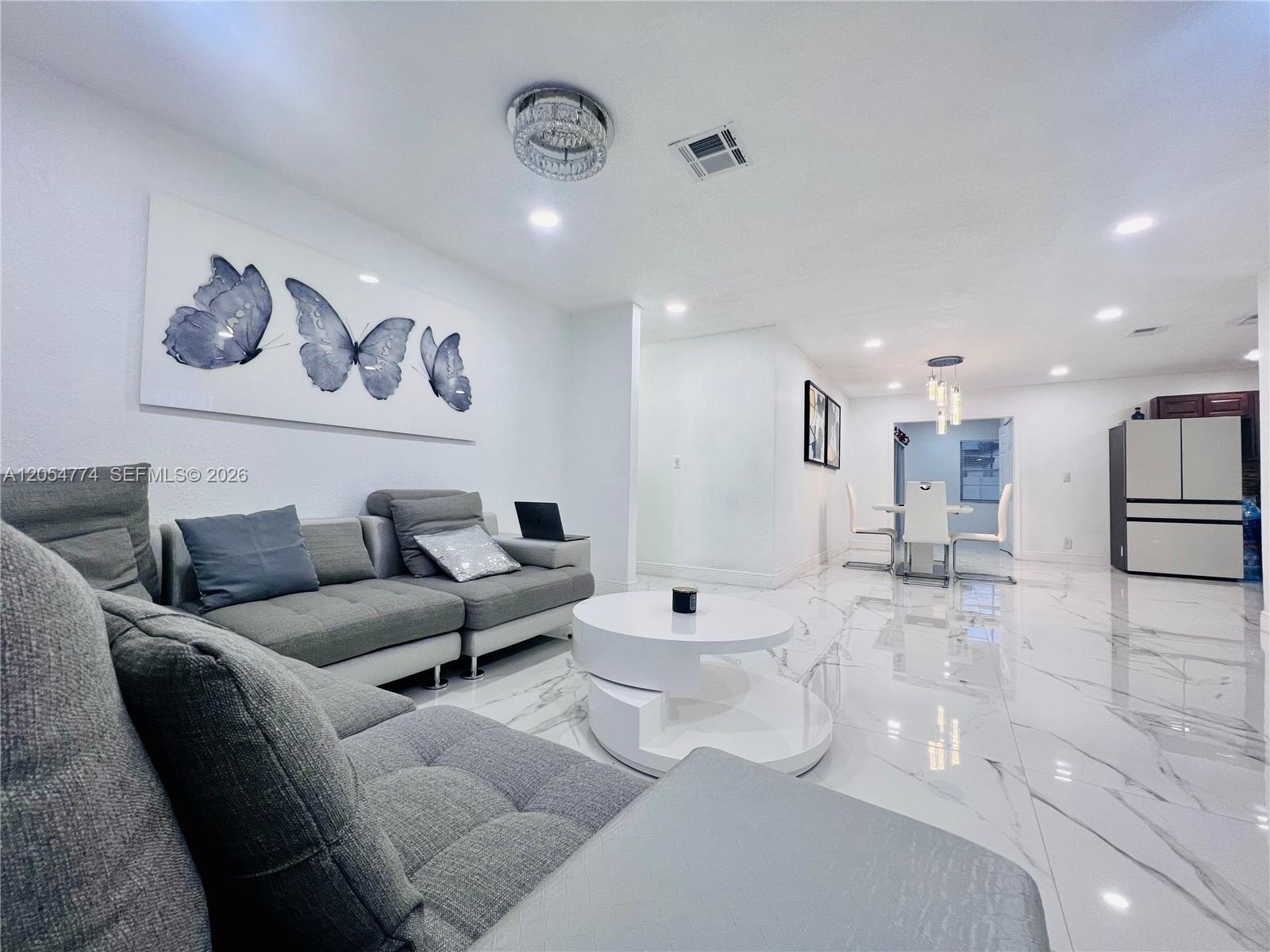 A modern living room features a grey sectional sofa, white coffee table, and marble flooring — 2001 SW 85th Ave, North Lauderdale FL 33068, NORTH LAUDERDALE, FL