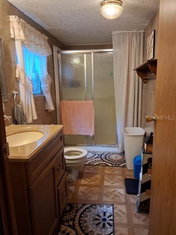A bathroom features a vanity, a toilet, a glass-enclosed shower, and tiled walls — 13600 NE 166TH STREET, FORT MC COY, FL