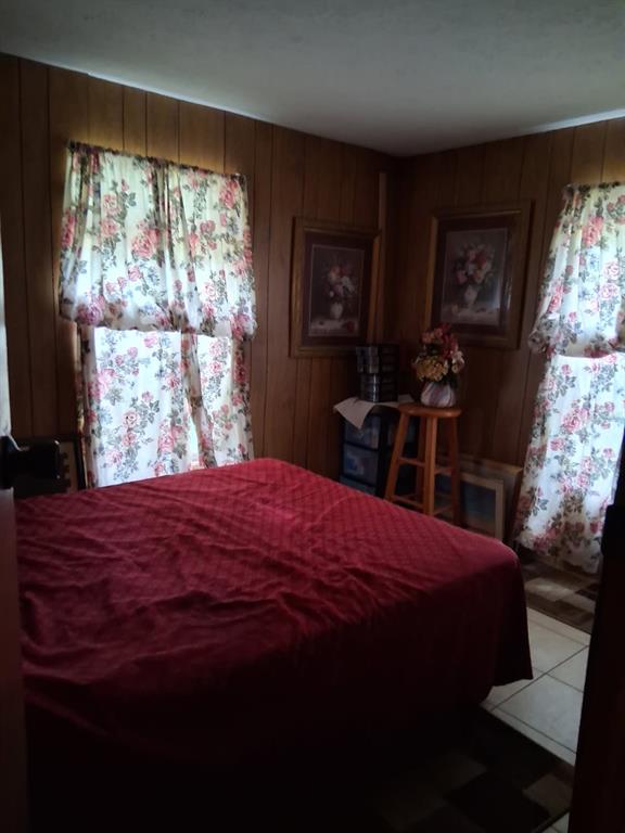 A bedroom features wood-paneled walls, a red bedspread, floral curtains, and a wooden stool — 13600 NE 166TH STREET, FORT MC COY, FL