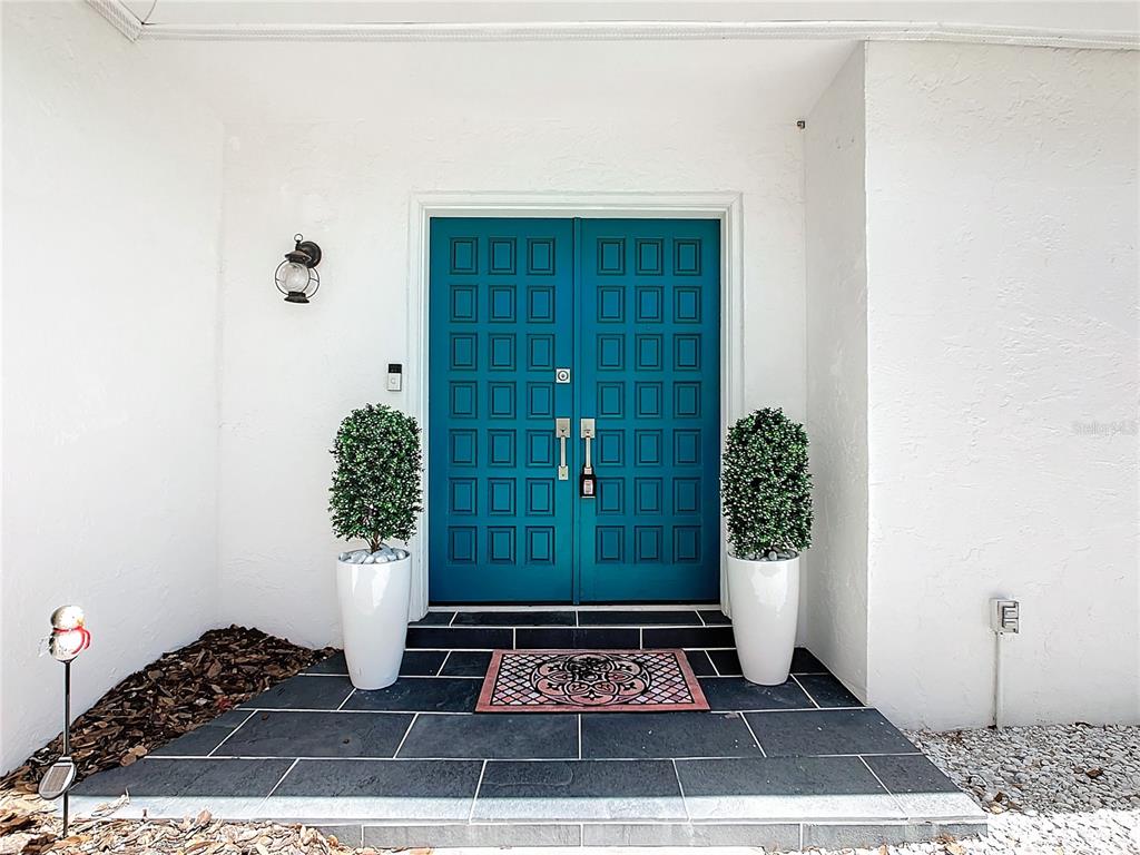 A teal double door entrance with two potted topiary plants on a tiled porch — 2250 WATROUS DR, DUNEDIN, FL